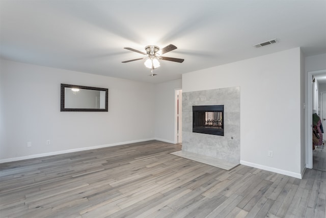 unfurnished living room with a tile fireplace, light hardwood / wood-style flooring, and ceiling fan