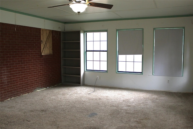 unfurnished room with ceiling fan, light colored carpet, and brick wall