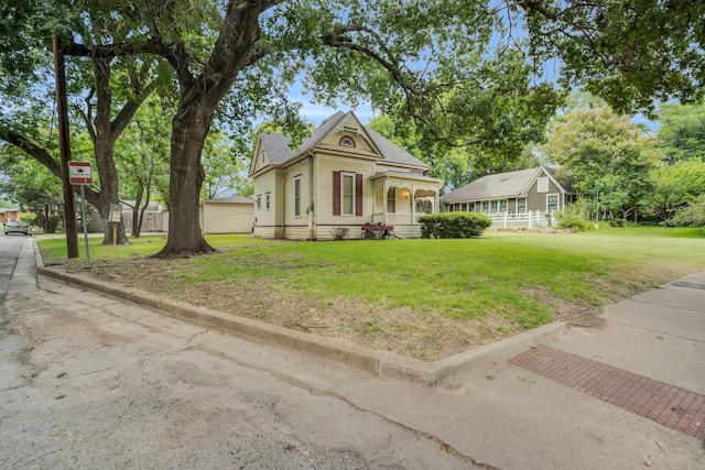 view of front of home featuring a front yard, a shed, and covered porch