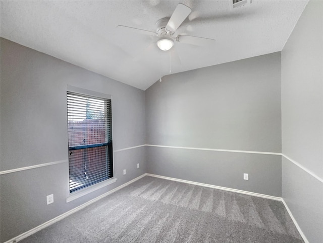 empty room with a textured ceiling, carpet floors, vaulted ceiling, and ceiling fan