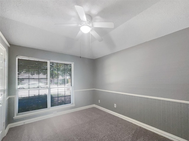 carpeted empty room featuring a textured ceiling, ceiling fan, and lofted ceiling