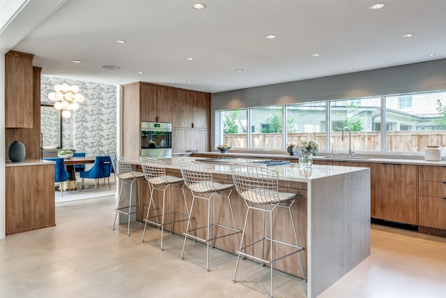 kitchen with a kitchen breakfast bar, a kitchen island, sink, and stainless steel oven