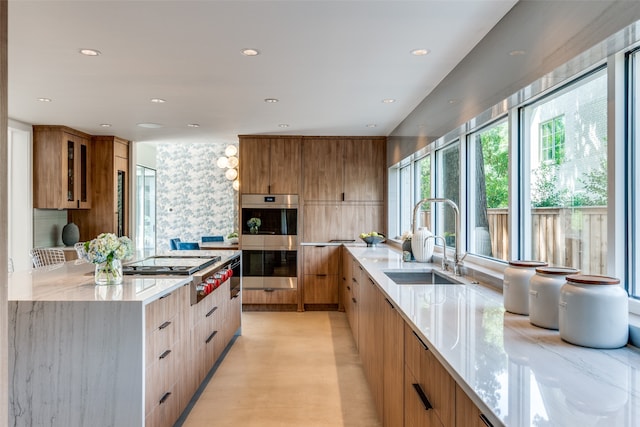 kitchen with sink, light stone counters, stainless steel appliances, and backsplash