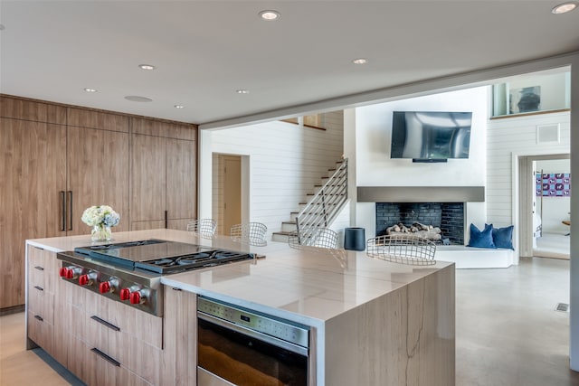 kitchen with appliances with stainless steel finishes, a center island, light stone counters, and wooden walls