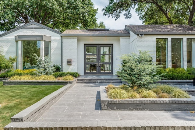 entrance to property with french doors and a lawn