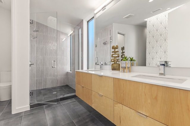 bathroom featuring tile patterned flooring, toilet, an enclosed shower, and dual bowl vanity