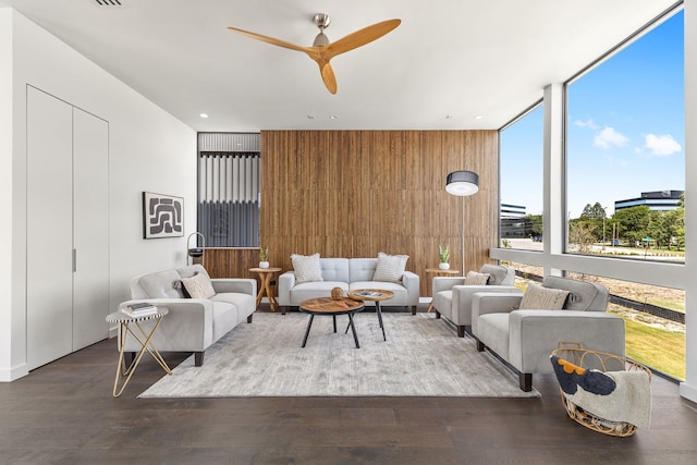 living room with ceiling fan, wood walls, hardwood / wood-style flooring, and floor to ceiling windows