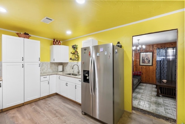 kitchen featuring sink, crown molding, stainless steel fridge, white cabinets, and decorative backsplash