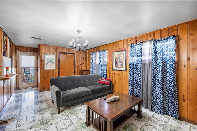 living room featuring an inviting chandelier and wood walls