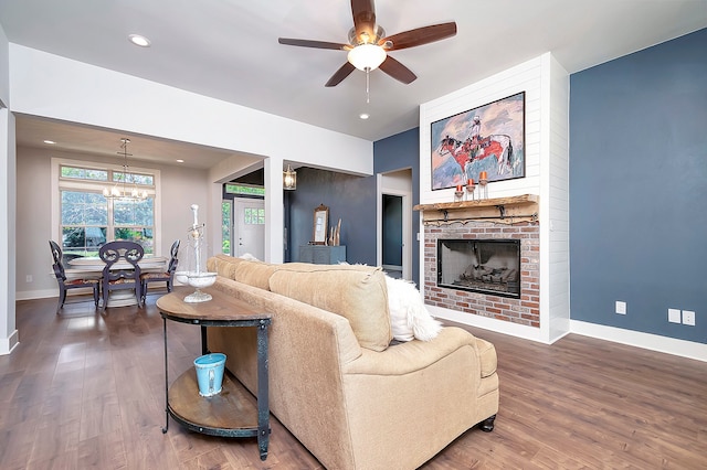 living room featuring dark hardwood / wood-style flooring, a fireplace, and ceiling fan with notable chandelier