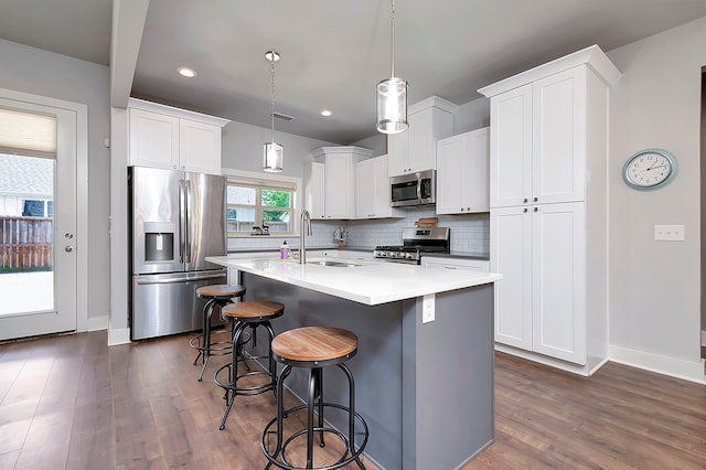 kitchen with backsplash, dark wood-type flooring, stainless steel appliances, hanging light fixtures, and sink