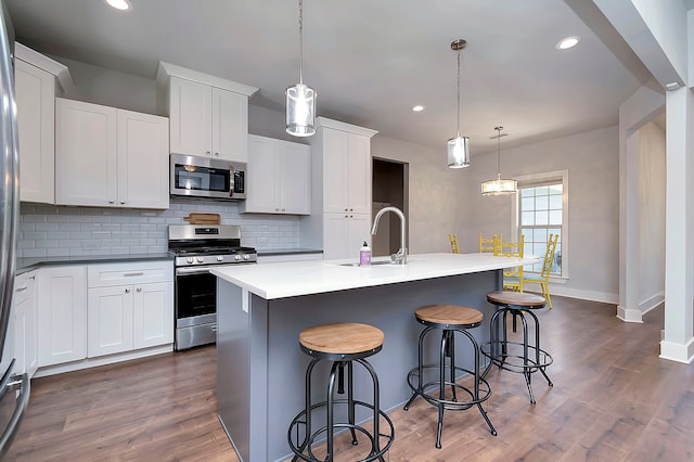 kitchen featuring tasteful backsplash, stainless steel appliances, dark hardwood / wood-style flooring, pendant lighting, and sink