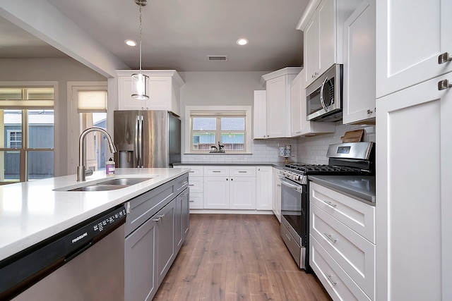 kitchen with tasteful backsplash, white cabinets, dark wood-type flooring, appliances with stainless steel finishes, and sink