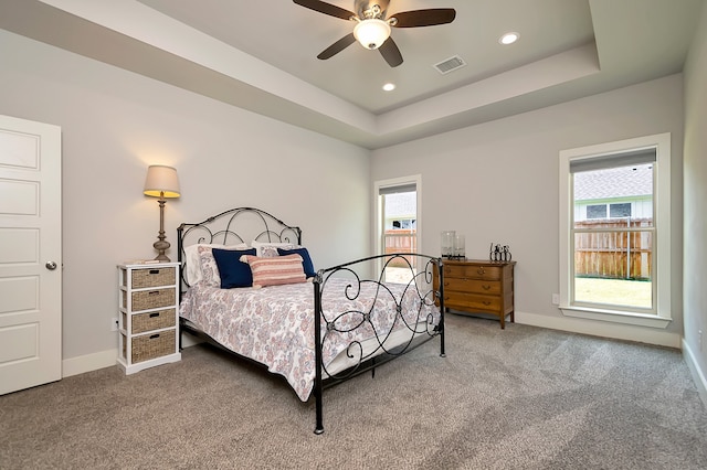 carpeted bedroom featuring ceiling fan and a raised ceiling