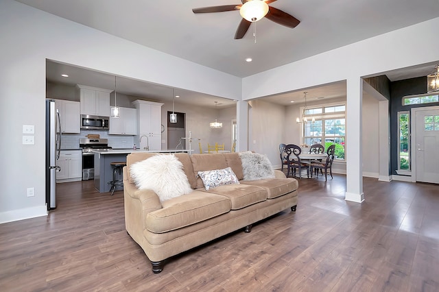 living room with sink, ceiling fan with notable chandelier, and hardwood / wood-style flooring