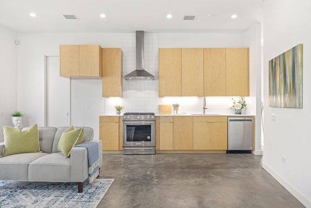 kitchen with appliances with stainless steel finishes, tasteful backsplash, sink, concrete flooring, and wall chimney exhaust hood