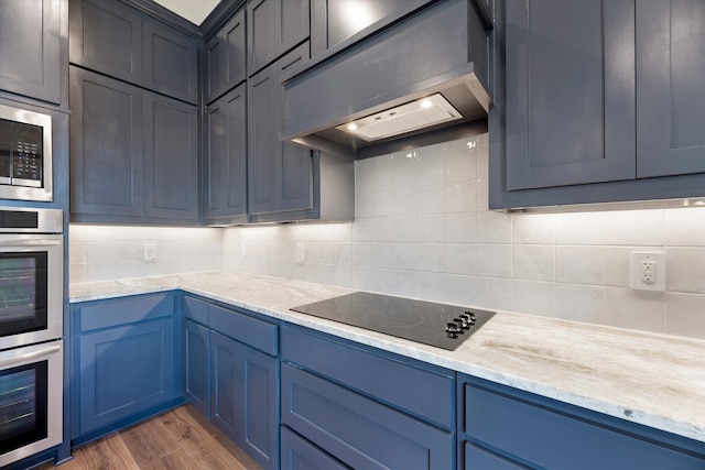 kitchen featuring blue cabinets, appliances with stainless steel finishes, tasteful backsplash, dark wood-type flooring, and light stone counters