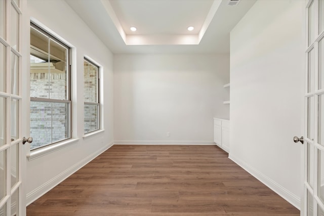 unfurnished room featuring a raised ceiling, dark hardwood / wood-style flooring, and french doors