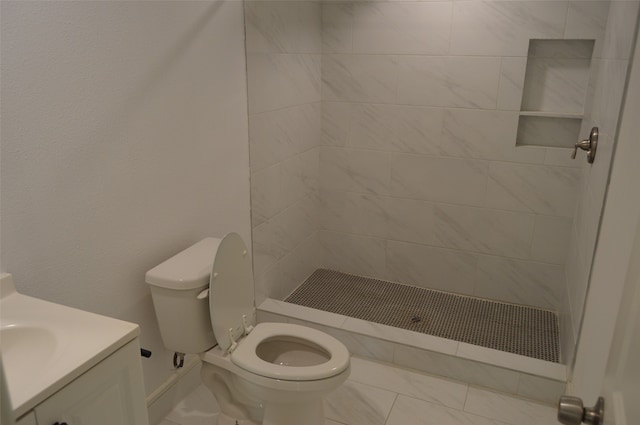 bathroom featuring tile patterned floors, vanity, tiled shower, and toilet