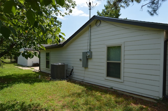 back of property featuring central air condition unit and a lawn