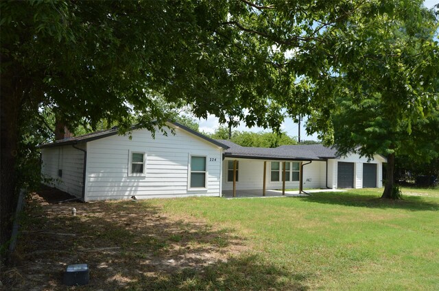 back of property featuring a garage and a yard