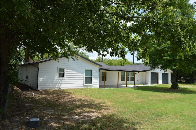 back of property featuring a garage and a lawn