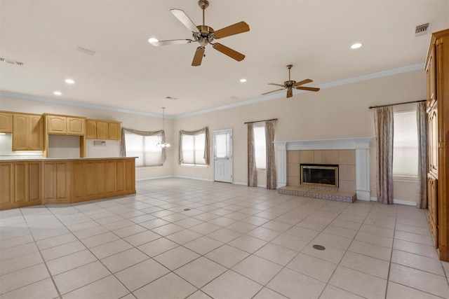 unfurnished living room with ornamental molding, ceiling fan, a tile fireplace, and light tile patterned flooring