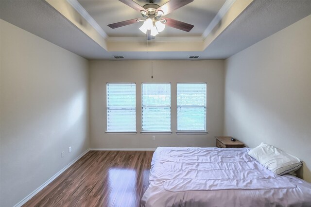 unfurnished bedroom with ornamental molding, hardwood / wood-style floors, ceiling fan, and a raised ceiling