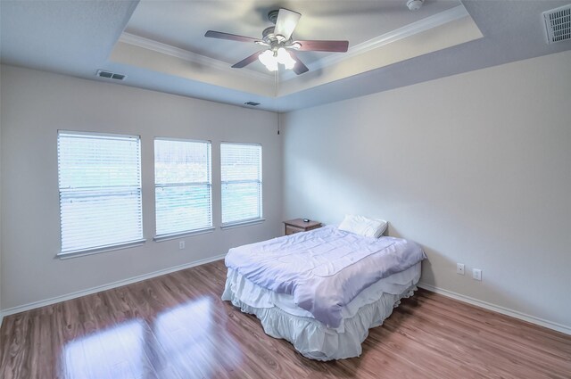 bedroom featuring ceiling fan, hardwood / wood-style flooring, crown molding, and a tray ceiling