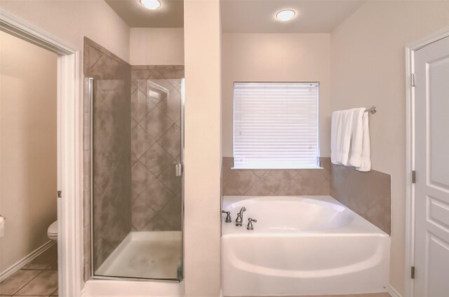 bathroom featuring tile patterned flooring, shower with separate bathtub, and toilet