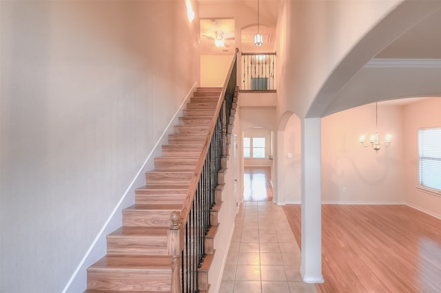 stairs featuring ornamental molding, hardwood / wood-style flooring, a notable chandelier, and a towering ceiling