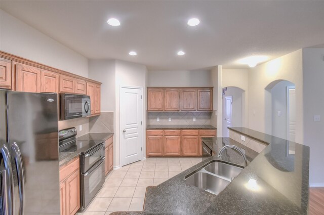 kitchen with light tile patterned flooring, a center island, black appliances, decorative backsplash, and sink