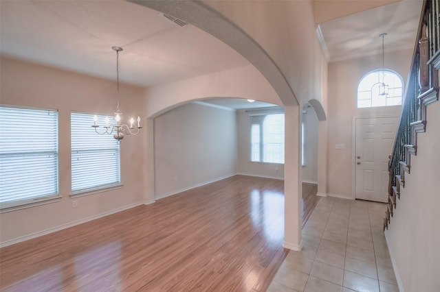 9816 Mullins Crossing Dr, Fort Worth, TX 76126 - foyer featuring a chandelier, arched walkways, baseboards, light wood finished floors, and stairs