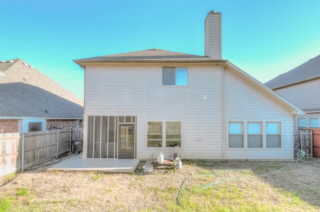 back of property with a sunroom and a lawn