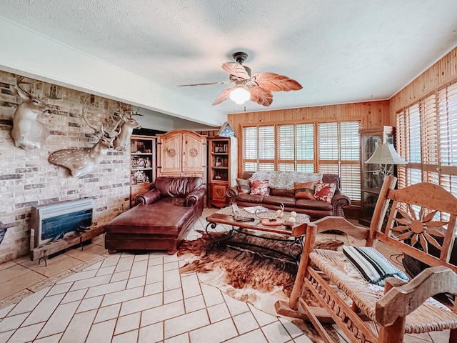 tiled living room featuring ceiling fan, a textured ceiling, and wooden walls