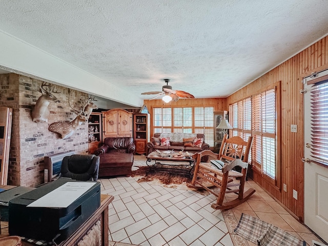 living room featuring a textured ceiling, ceiling fan, and wooden walls