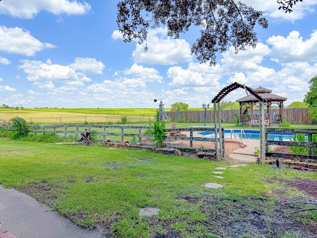 view of yard with a fenced in pool, a rural view, and a gazebo