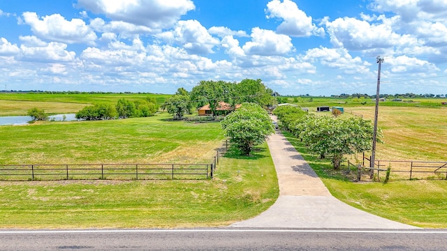 view of community with a rural view, a water view, and a lawn