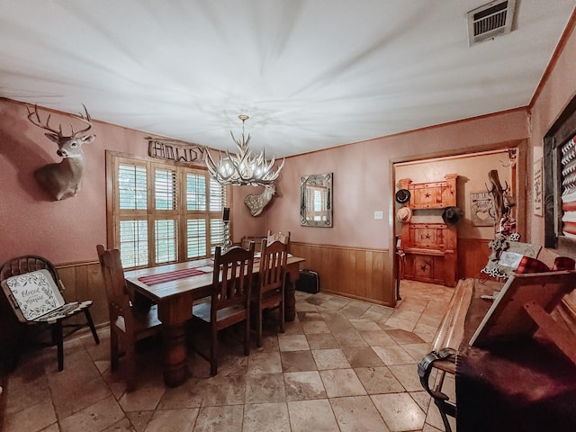 dining space with a notable chandelier and wood walls