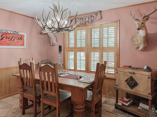 dining room with an inviting chandelier, crown molding, and wood walls