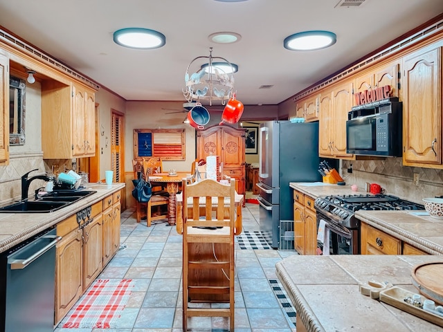 kitchen featuring light tile patterned floors, tile countertops, stainless steel appliances, tasteful backsplash, and sink