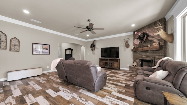 living room featuring brick wall, a brick fireplace, hardwood / wood-style floors, and ceiling fan