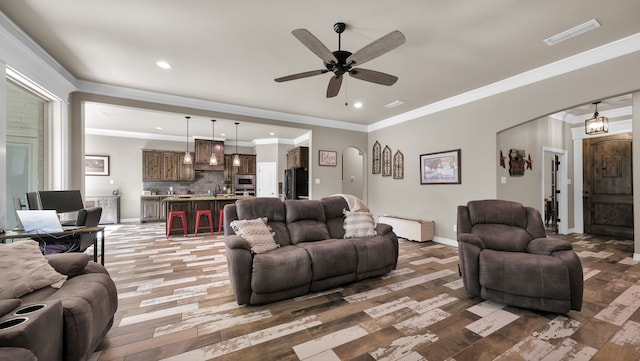 living room featuring wood-type flooring, ornamental molding, and ceiling fan