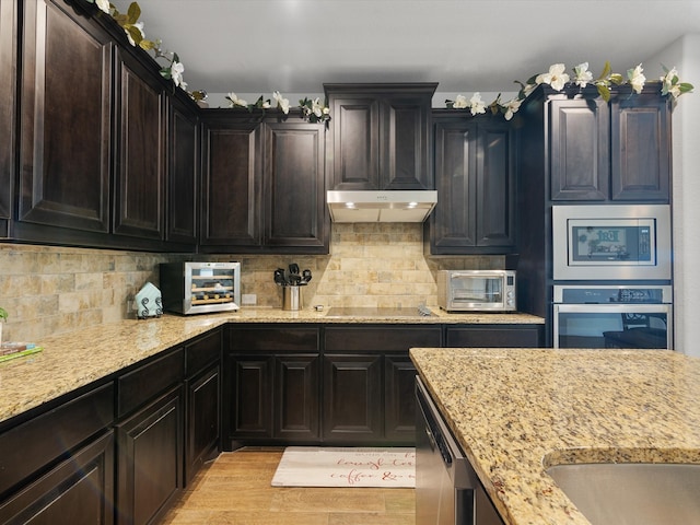 kitchen with light stone counters, stainless steel appliances, light wood-type flooring, and tasteful backsplash