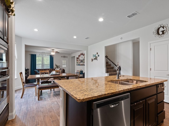 kitchen with a kitchen island with sink, stainless steel appliances, sink, light hardwood / wood-style floors, and ceiling fan