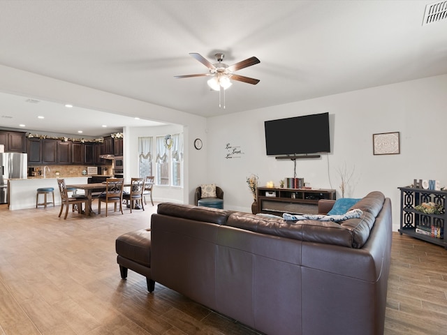 living room with ceiling fan and light wood-type flooring