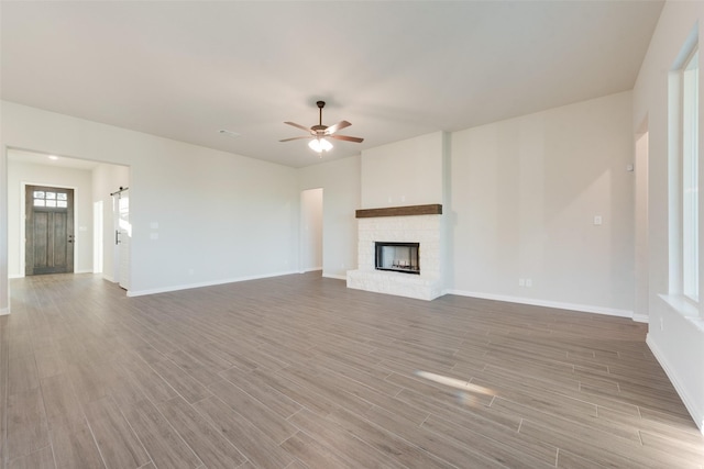 unfurnished living room with ceiling fan and a stone fireplace