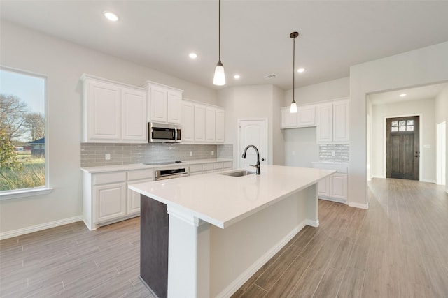 kitchen featuring stainless steel appliances, an island with sink, sink, and white cabinets