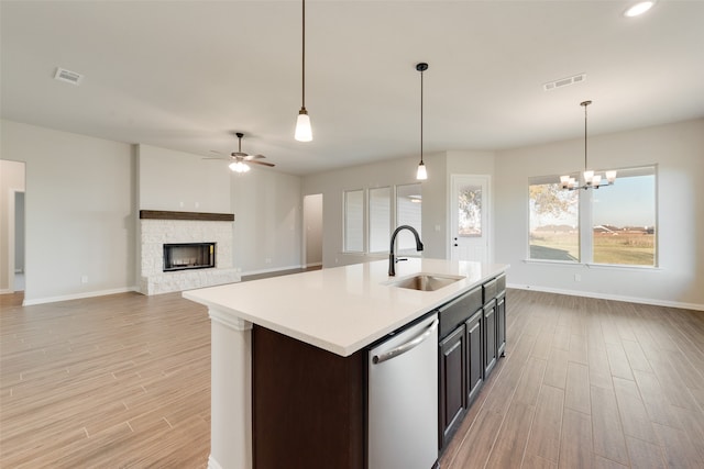 kitchen featuring sink, a stone fireplace, dishwasher, and light wood-type flooring