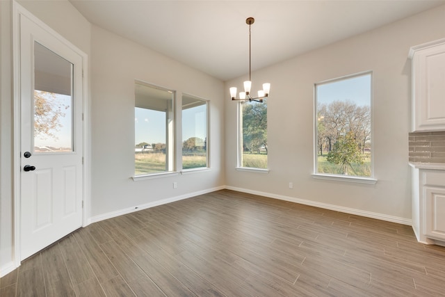 unfurnished dining area featuring an inviting chandelier and light wood-type flooring